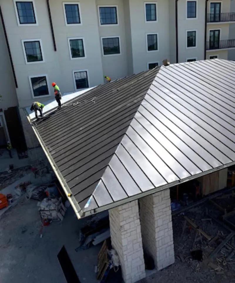 Crew installing standing seam metal roof panels on a commercial project in North Dansville